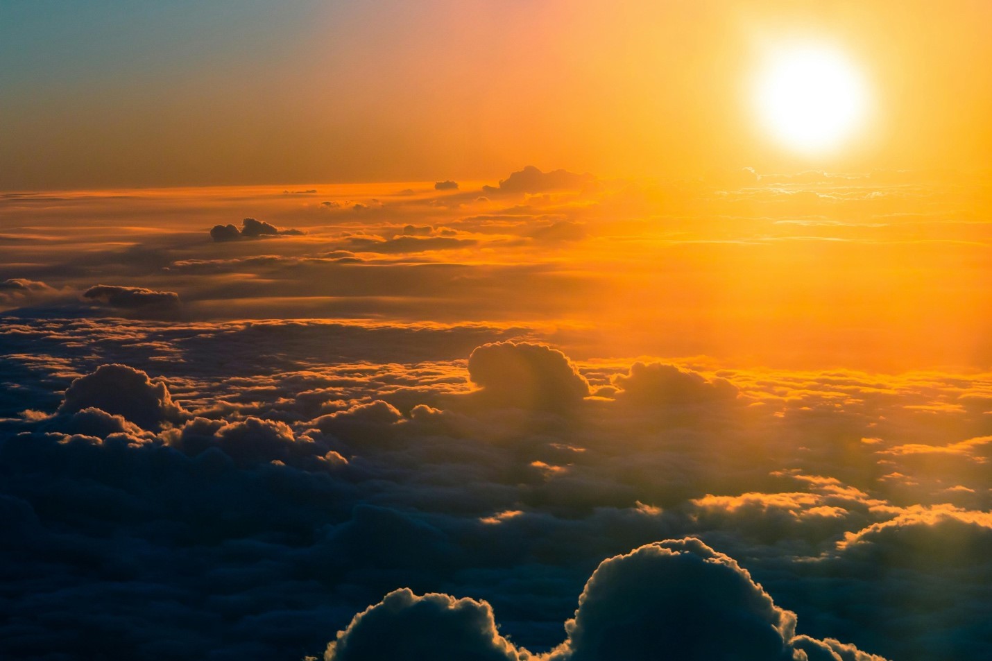 The sun setting, pictured from a very high altitude above the clouds. When a TV communication satellite is positioned between the Earth and the sun, it causes a sun outage for users on the ground.